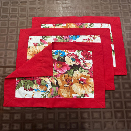 Set of floral placemats with red borders on a textured surface